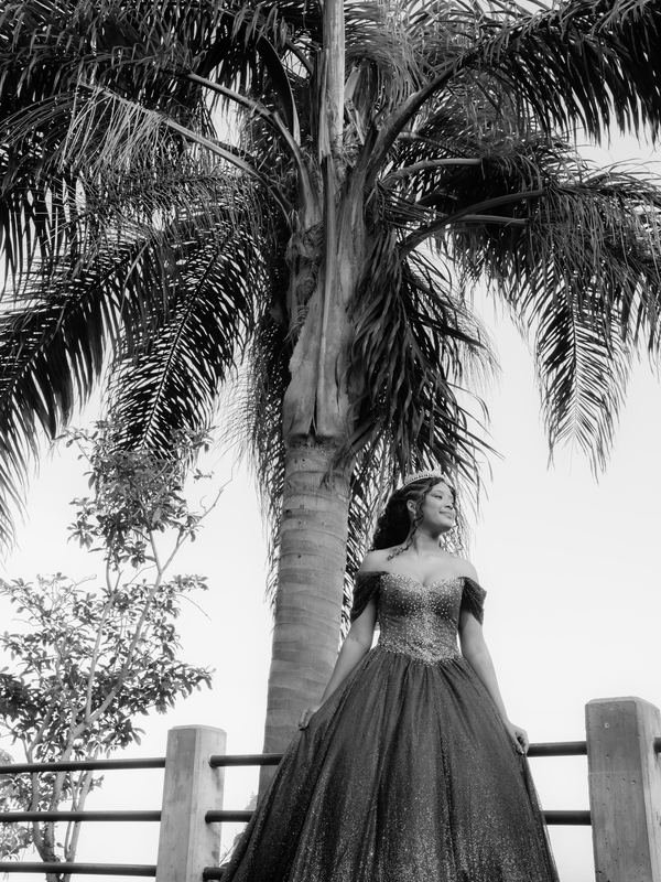 Larissa de vestido junto à palmeira, em preto e branco