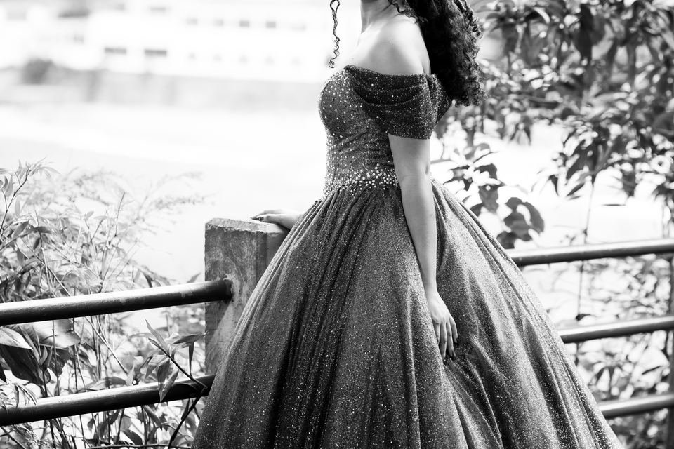 Larissa de vestido junto à cerca, em preto e branco